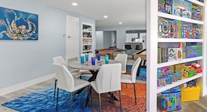 A children's play area with a table, chairs, and a bookshelf filled with toys and games. - #1 Destin home, Saltwater spa & pool, Beach@2min walk, Golf cart (Destin)