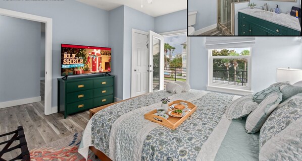 A modern bedroom with a TV, a green dresser, a bed with a floral bedspread, and a view of the outdoors. - #1 Destin home, Saltwater spa & pool, Beach@2min walk, Golf cart (Destin)