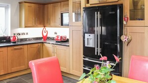 Una cocina moderna con armarios de madera, un refrigerador negro y una mesa de comedor con sillas rojas.