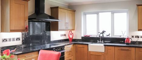 A modern kitchen with wooden cabinets, a black stove, and a window with natural light.