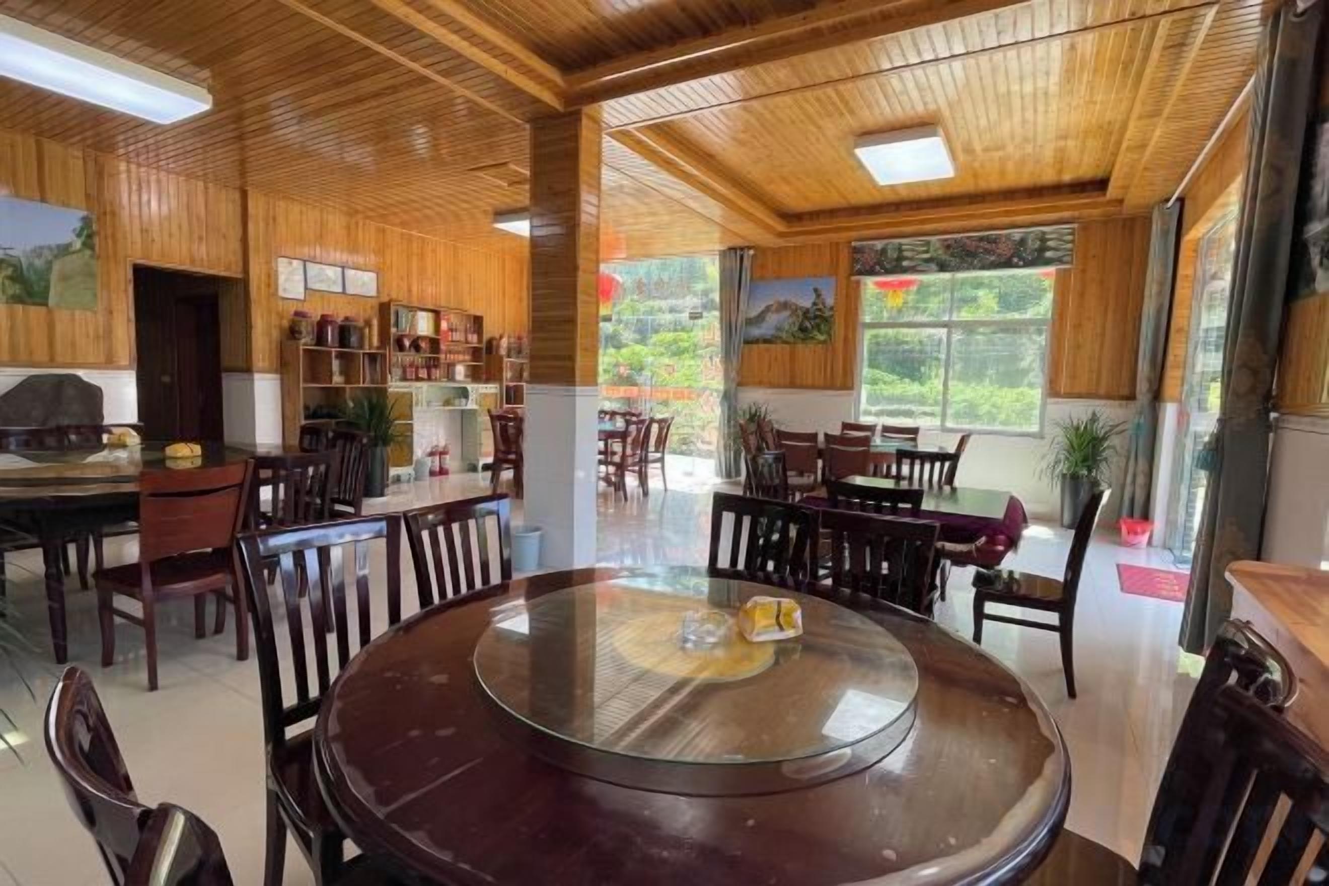 Un comedor amplio con una mesa redonda, techo de madera y ventanas grandes.