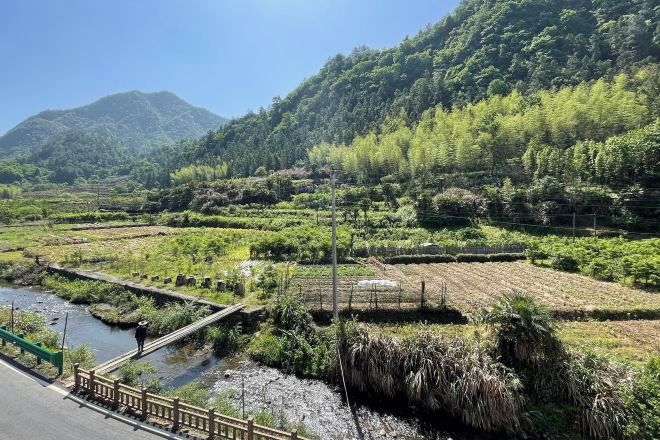 A rural landscape with terraced fields, a bridge, and a river.