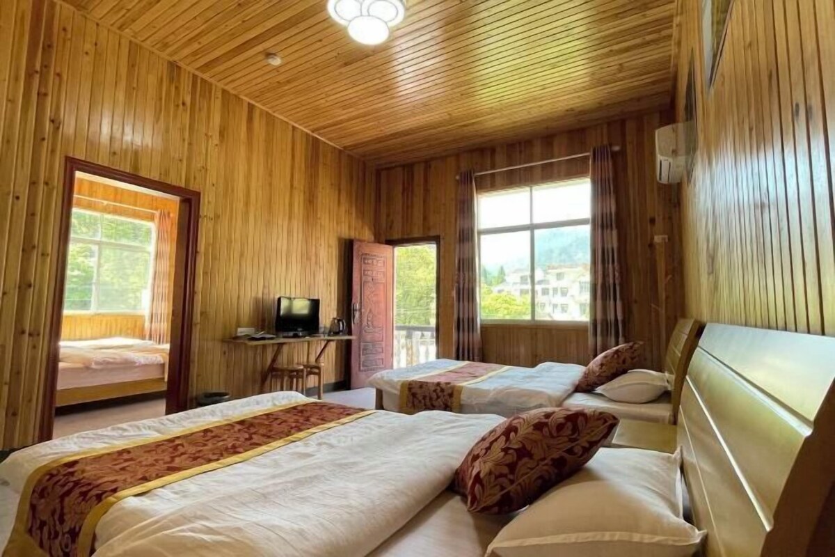 A wooden cabin room with two beds, a desk, and a television.