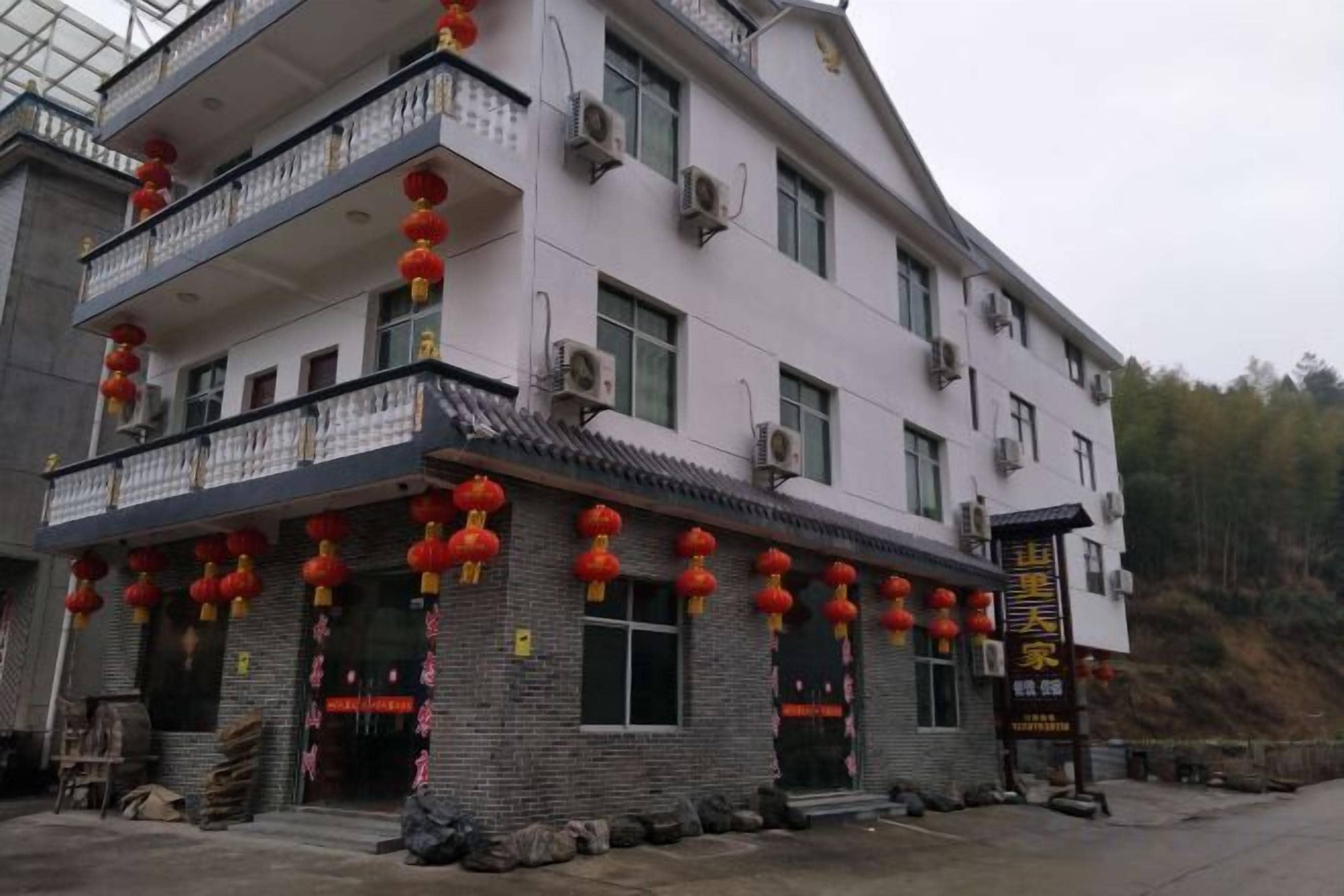 A multi-story building with balconies, air conditioning units, and a signboard.