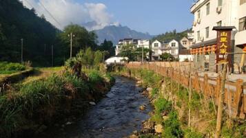 A river flowing through a residential area with houses on one side and a mountain in the background.