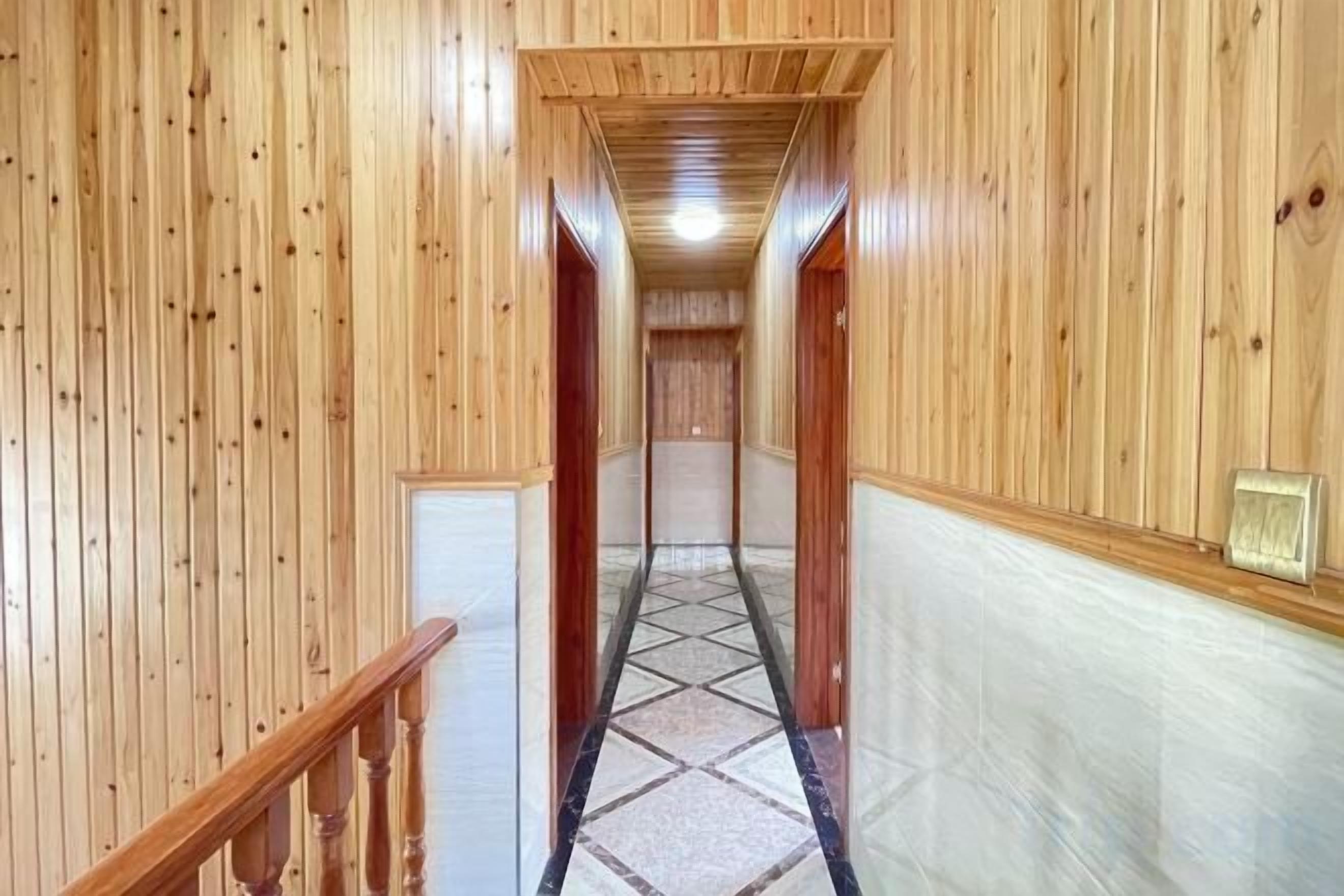 A wooden hallway with a carpeted floor and a wooden railing on the left.