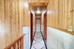 Un couloir en bois, doté d’un plancher recouvert de moquette et d’une rambarde en bois sur le côté gauche.