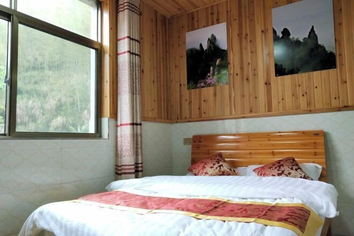 A bedroom with a wooden headboard, a bed with a white and red bedspread, and two framed pictures on the wall.