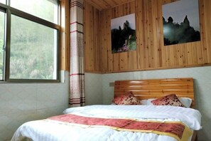 A bedroom with a wooden headboard, a bed with a white and red bedspread, and two framed pictures on the wall. - Shanlirenjia Inn Sanqingshan (Yushan)