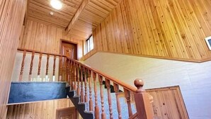 Eine Holztreppe mit Handlauf und einem dunkel gefärbten Landeplatz.