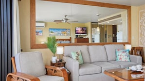 A living room with a sofa, two wooden chairs, a coffee table, a TV, and a ceiling fan. - KBM Resorts: Papakea Pke-304 Renovated Studio With Ocean Views! (Kaanapali)