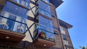 A multi-story building with large windows and a brick facade. - Loft cama Kingsize 3min centro turístico (Campos do Jordão)