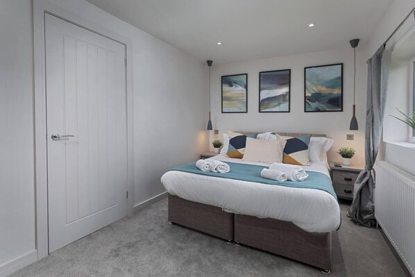 A bedroom with a large bed, a wardrobe, and three framed artworks on the wall. - Prime Location, Modern 2BR House (South Yorkshire)