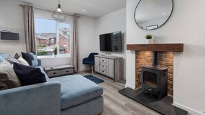 A modern living room with a sofa, TV, fireplace, and a view of the outside.