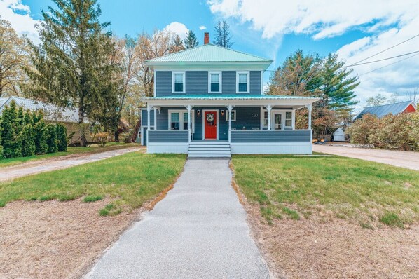 A two-story house with a red front door, a porch, and a small front yard. - Location!Location!Pets & hot tub (Conway)