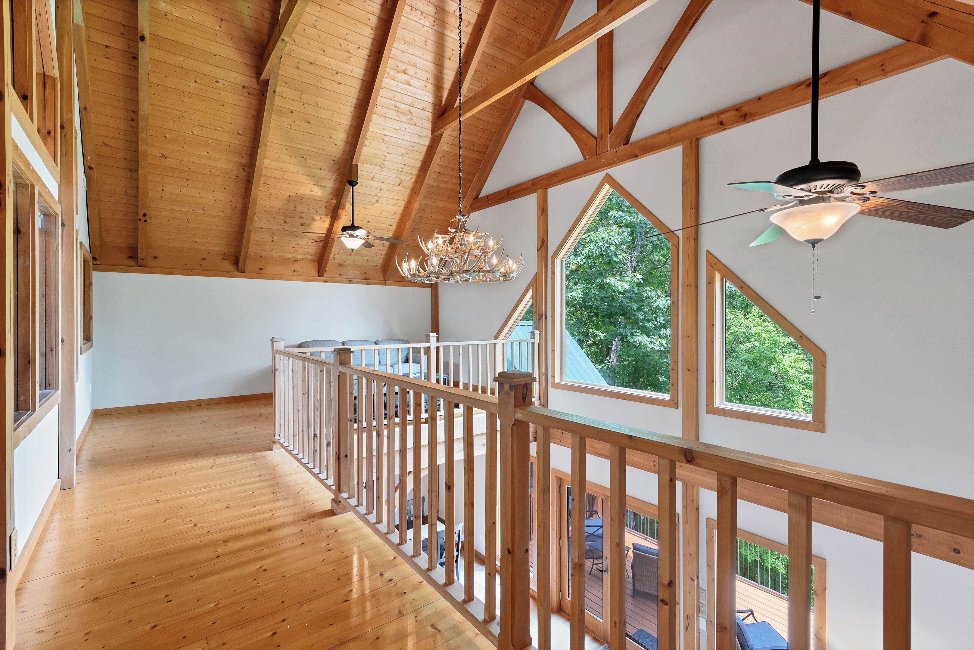 Ein Holzinnenraum mit Balkon, großen Fenstern und einer Chandelüstere.