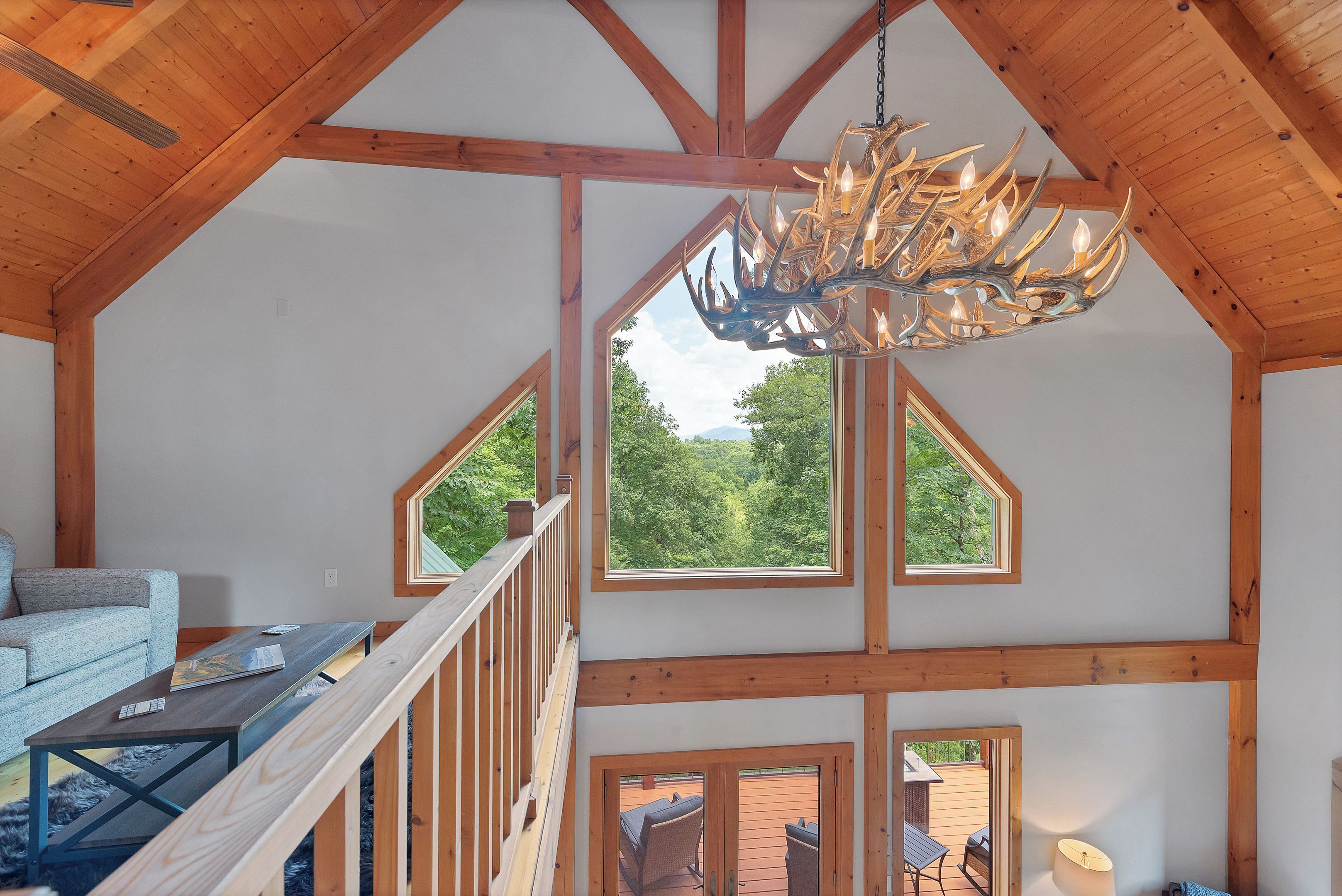 Un loft spacieux avec de hauts plafonds, des poutres apparentes et de grandes fenêtres offrant une vue sur l’extérieur.