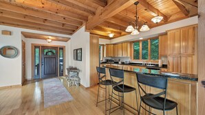 A spacious kitchen with wooden cabinets, a central island with bar stools, and a large window providing natural light. - This Amazing home has much to offer ,spacious rooms & and a hot-tub for relaxing (Townsend)