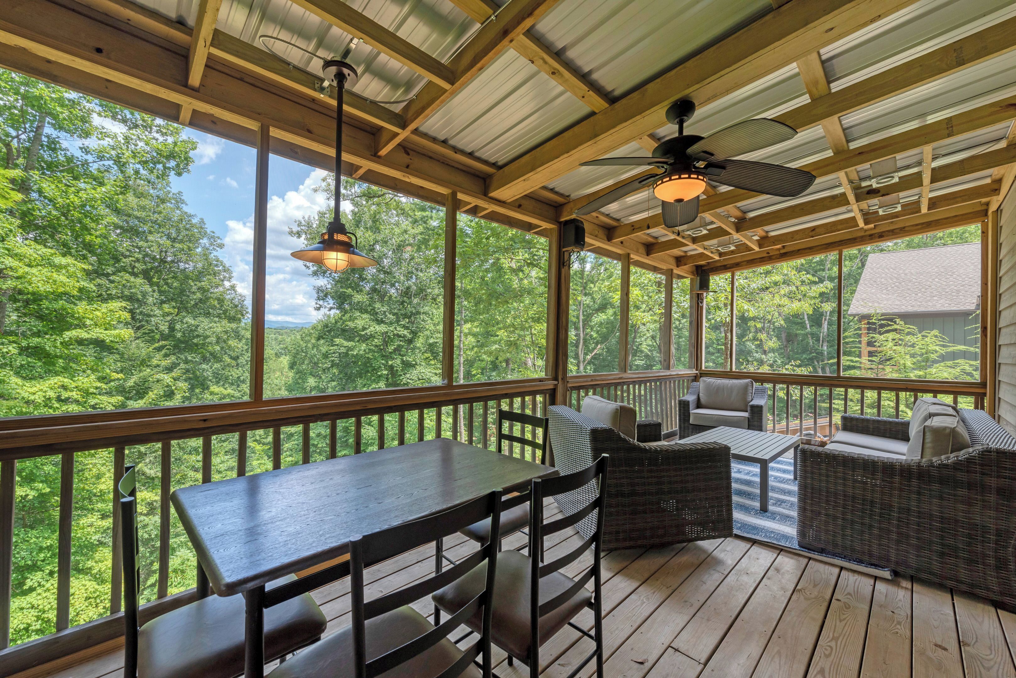 A covered outdoor deck with a table and chairs, a sofa, and a ceiling fan.