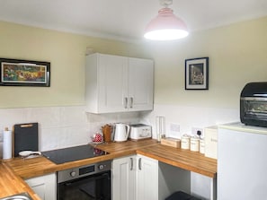 A compact kitchen with white cabinets, a black countertop, a coffee maker, a toaster, and a kettle.