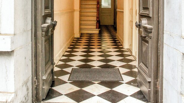 Un pasillo con piso a cuadros que lleva a una escalera.