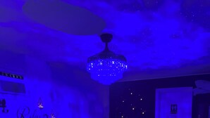 A bedroom with a bed, a chandelier, a fireplace, and a door with a sign.