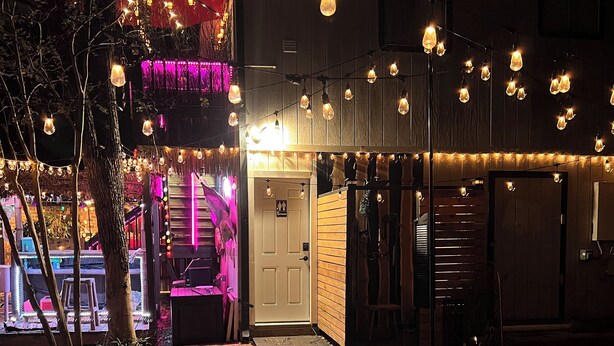 Un jacuzzi situé devant un bâtiment, décoré de guirlandes lumineuses et avec une porte.