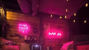 Un espace bien-être avec un jacuzzi, des enseignes lumineuses au néon et des murs en bois.