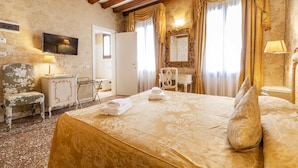 A hotel room with a bed, a desk, a chair, a television, and a mirror. - Ca di Malta Room 5 by Wonderful Italy (Venice)