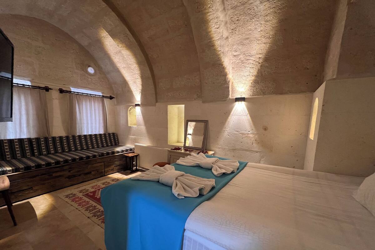 Une chambre à coucher avec un lit, un banc, un miroir et une fenêtre.