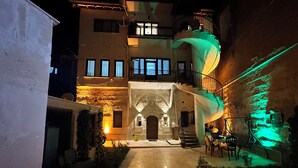 A courtyard with a spiral staircase, stone walls, and a central archway. - Uluyol Stone House (Avanos)