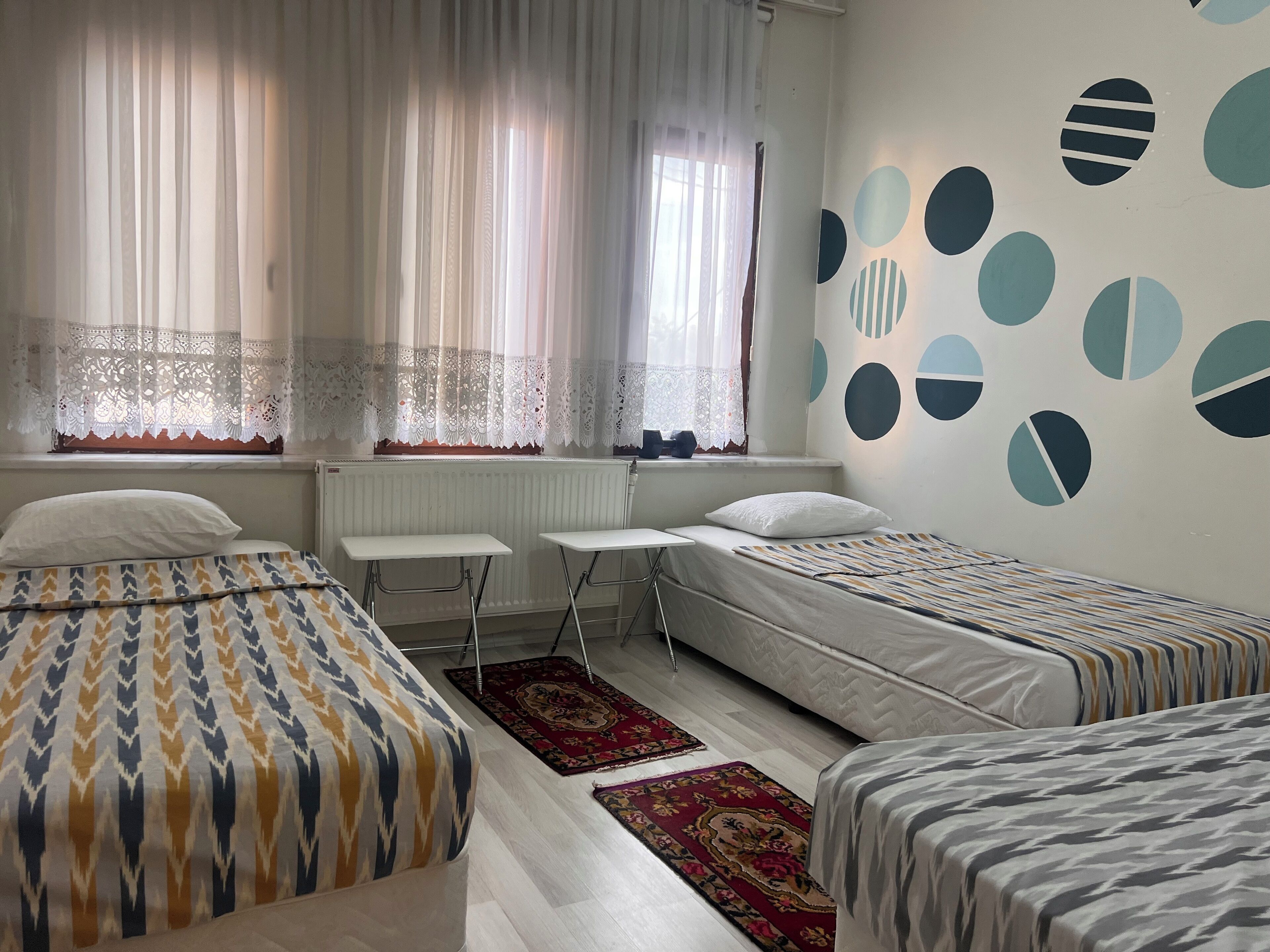 A room with two beds, a small table, and a radiator.
