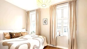 Une chambre à coucher avec un lit, des rideaux, une fenêtre et un tableau accroché au mur.