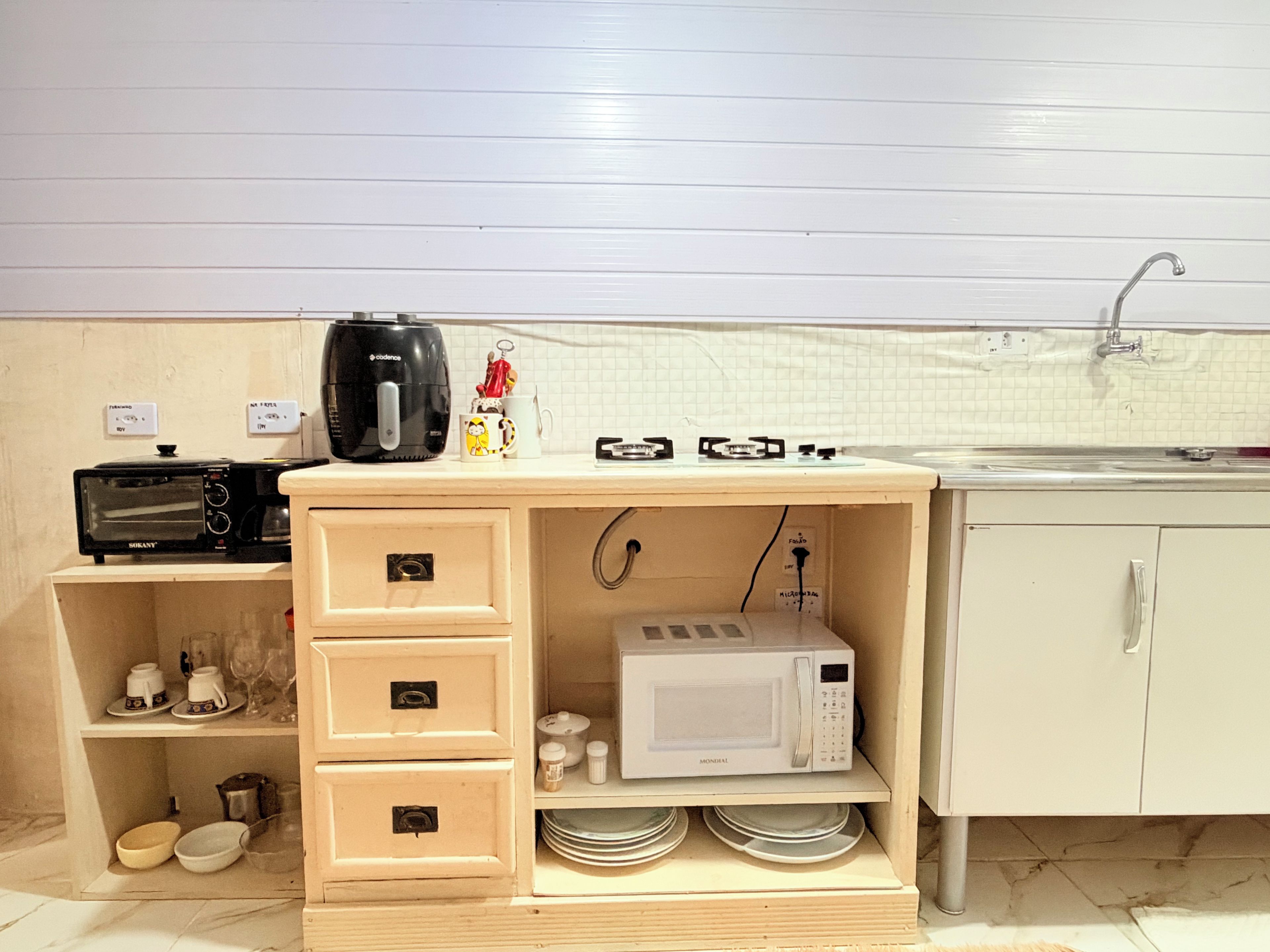 A kitchenette with a toaster, coffee maker, microwave, and a sink.
