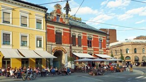 Un espace café animé en plein air, avec des tables et des chaises, entouré de bâtiments historiques à l’architecture remarquable.