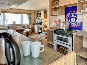 Une cuisine compacte pour camping-car, équipée d’une cuisinière, d’un four et d’un coin repas avec une banquette.