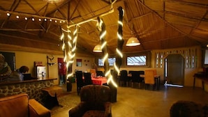 A spacious lobby with a high ceiling, stone walls, and a central seating area with a patterned armchair. - Oseki Maasai Mara Camp-Affordable Glamping Tents Available Hosted by Maasai. (Sekanani Town)