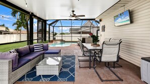 Un patio techado con piscina, mobiliario exterior y un ventilador de techo.