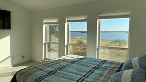 Una camera da letto con un letto grande, tre finestre e vista su un corpo d'acqua.