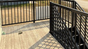 A wooden deck with a metal railing overlooking a mountainous landscape with a ski lift in the distance.