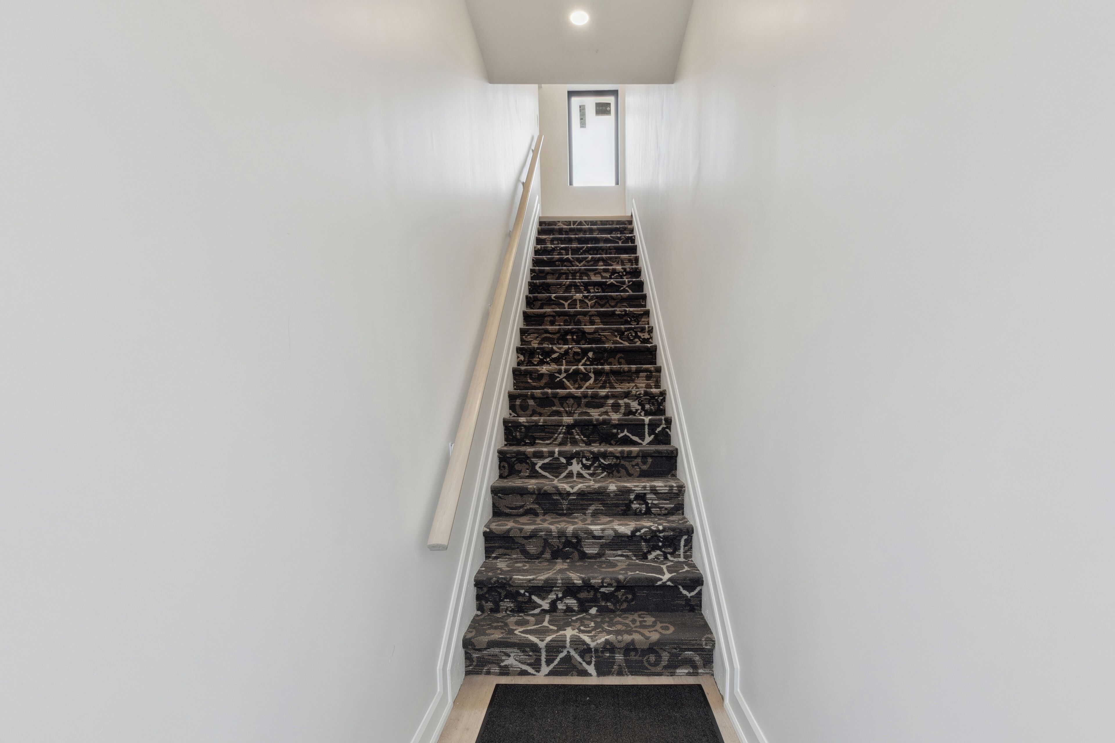A staircase with patterned carpet leading to a door at the top.