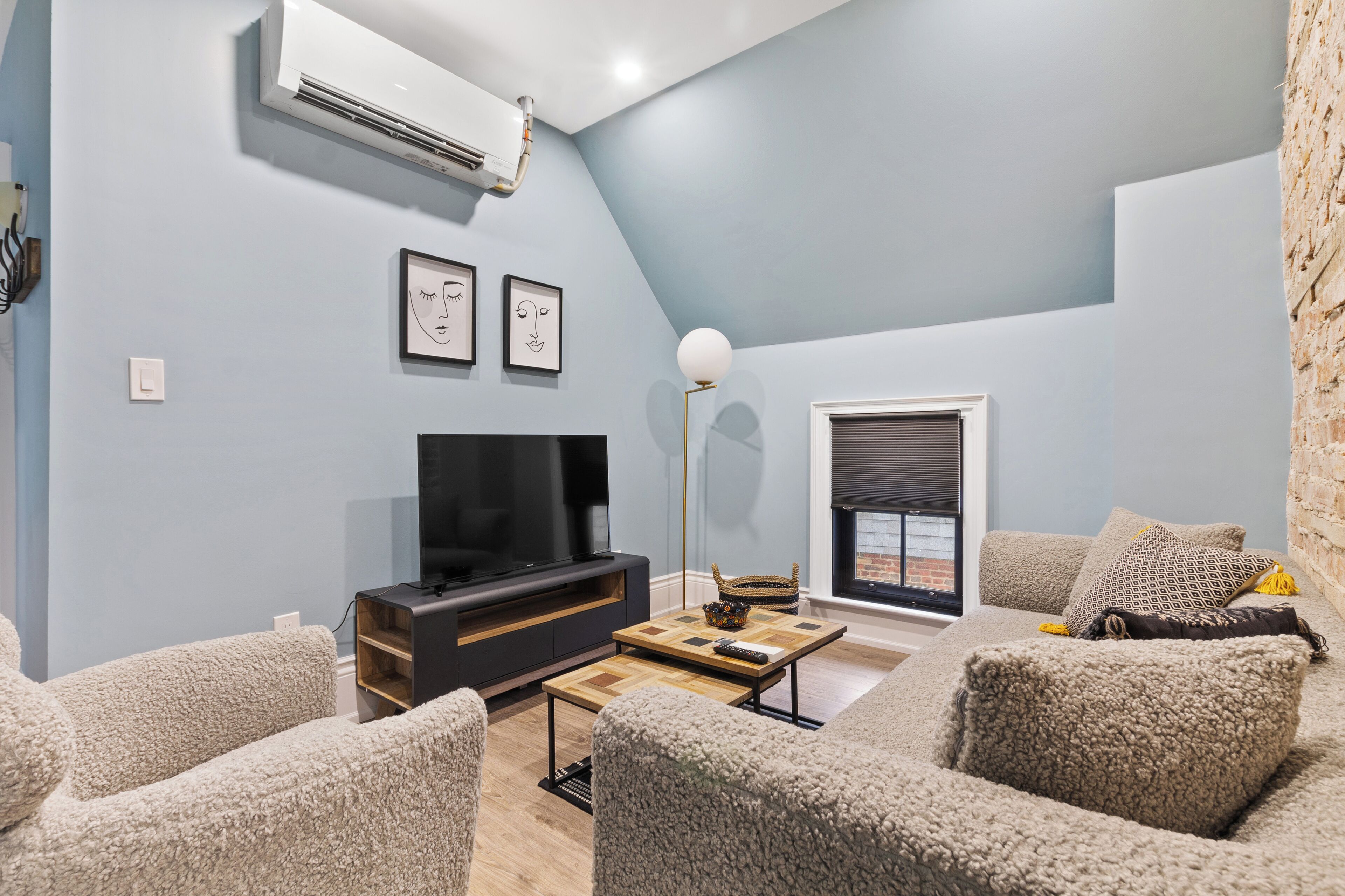 Una sala de estar moderna con televisor de pantalla plana, chimenea y un ventanal grande.