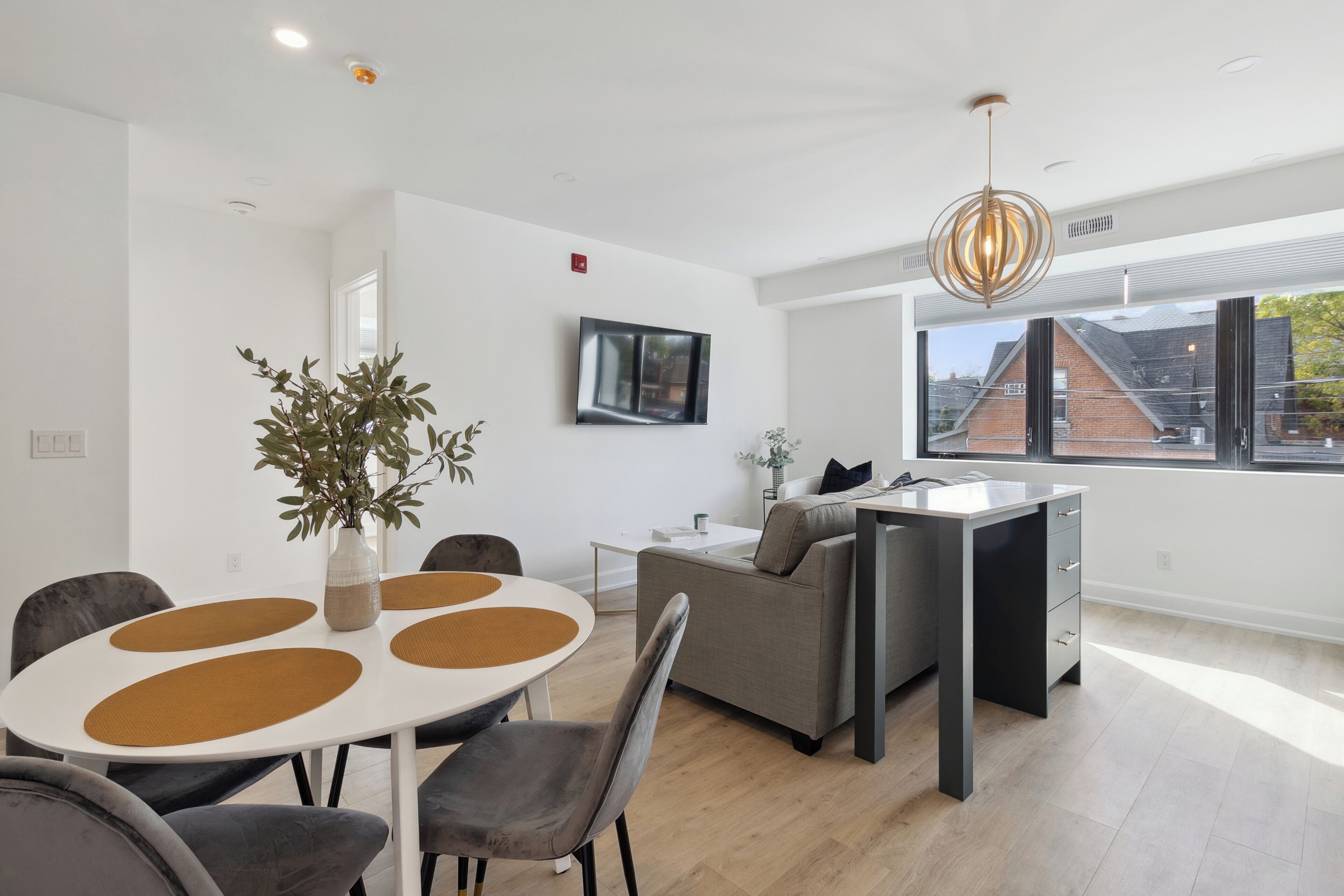 Una sala de estar moderna con comedor, un sofá, una mesa de centro y un amplio ventanal con vistas al exterior.