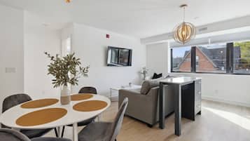 Una sala de estar moderna con comedor, un sofá, una mesa de centro y un amplio ventanal con vistas al exterior.