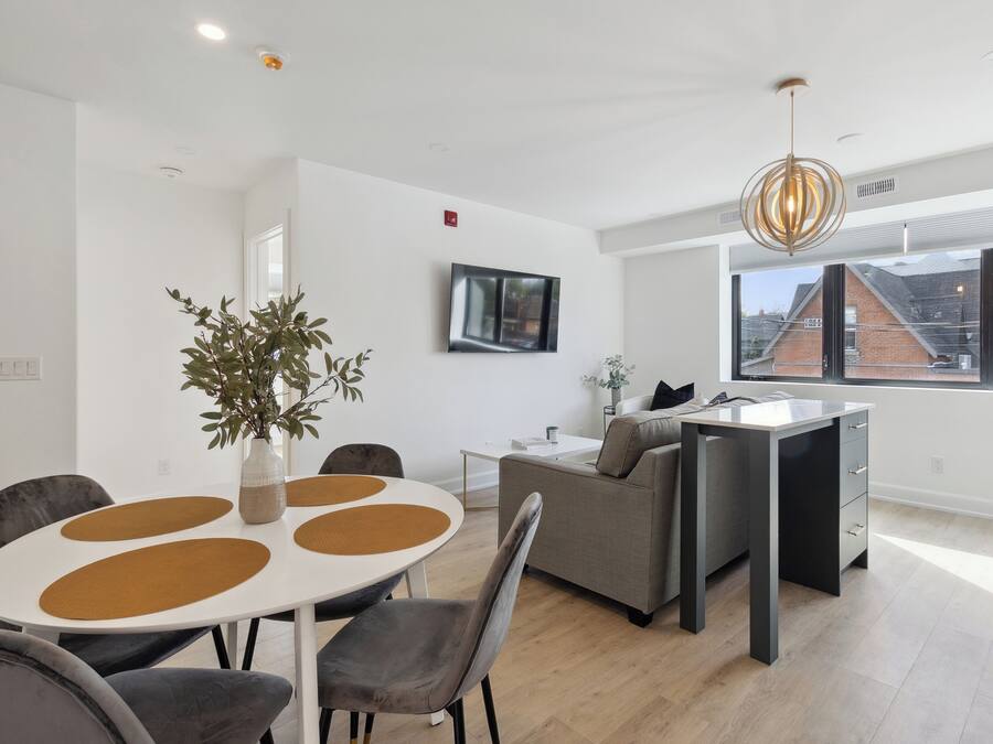 Una sala de estar moderna con comedor, un sofá, una mesa de centro y un amplio ventanal con vistas al exterior.