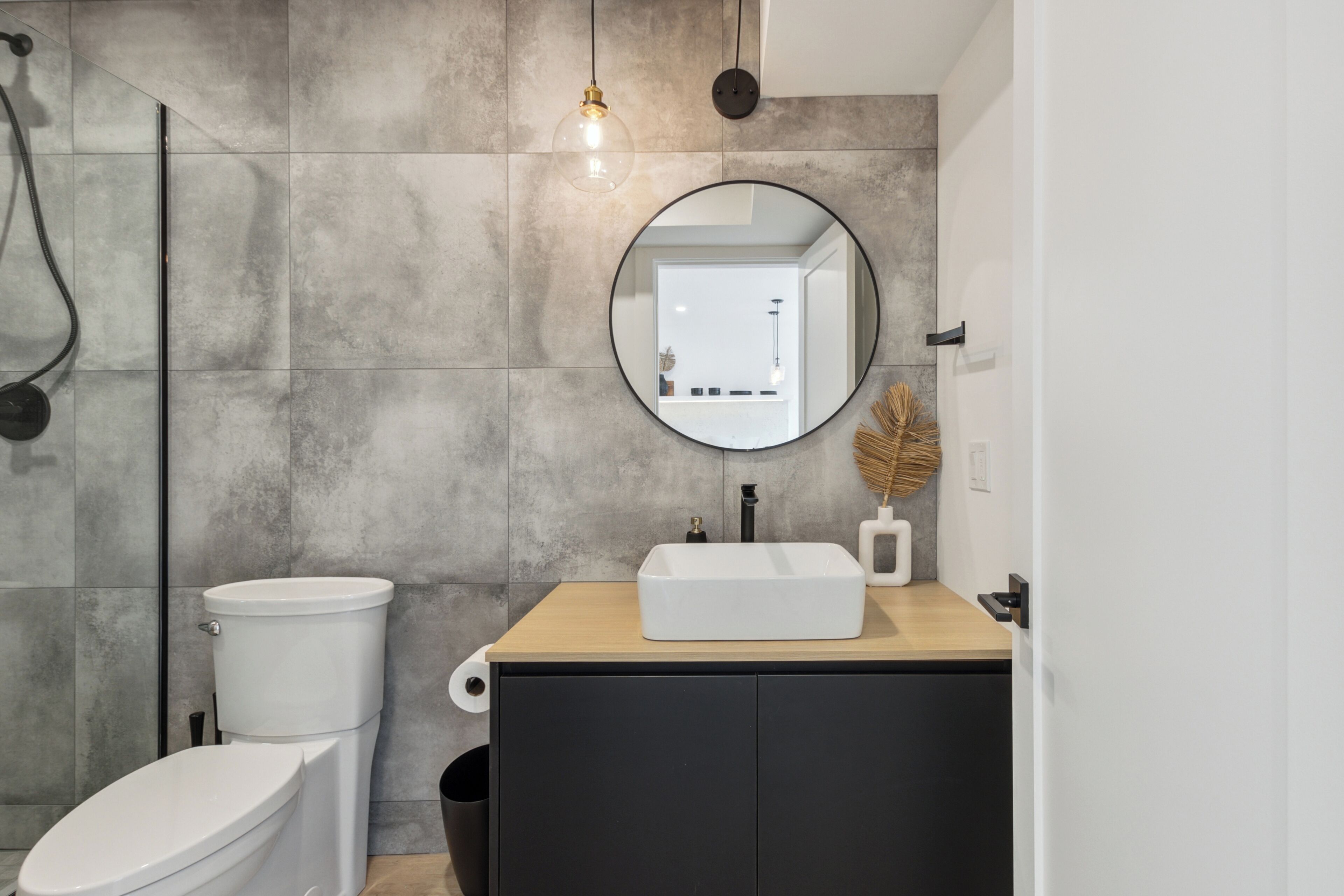A modern bathroom with a toilet, sink, and mirror.