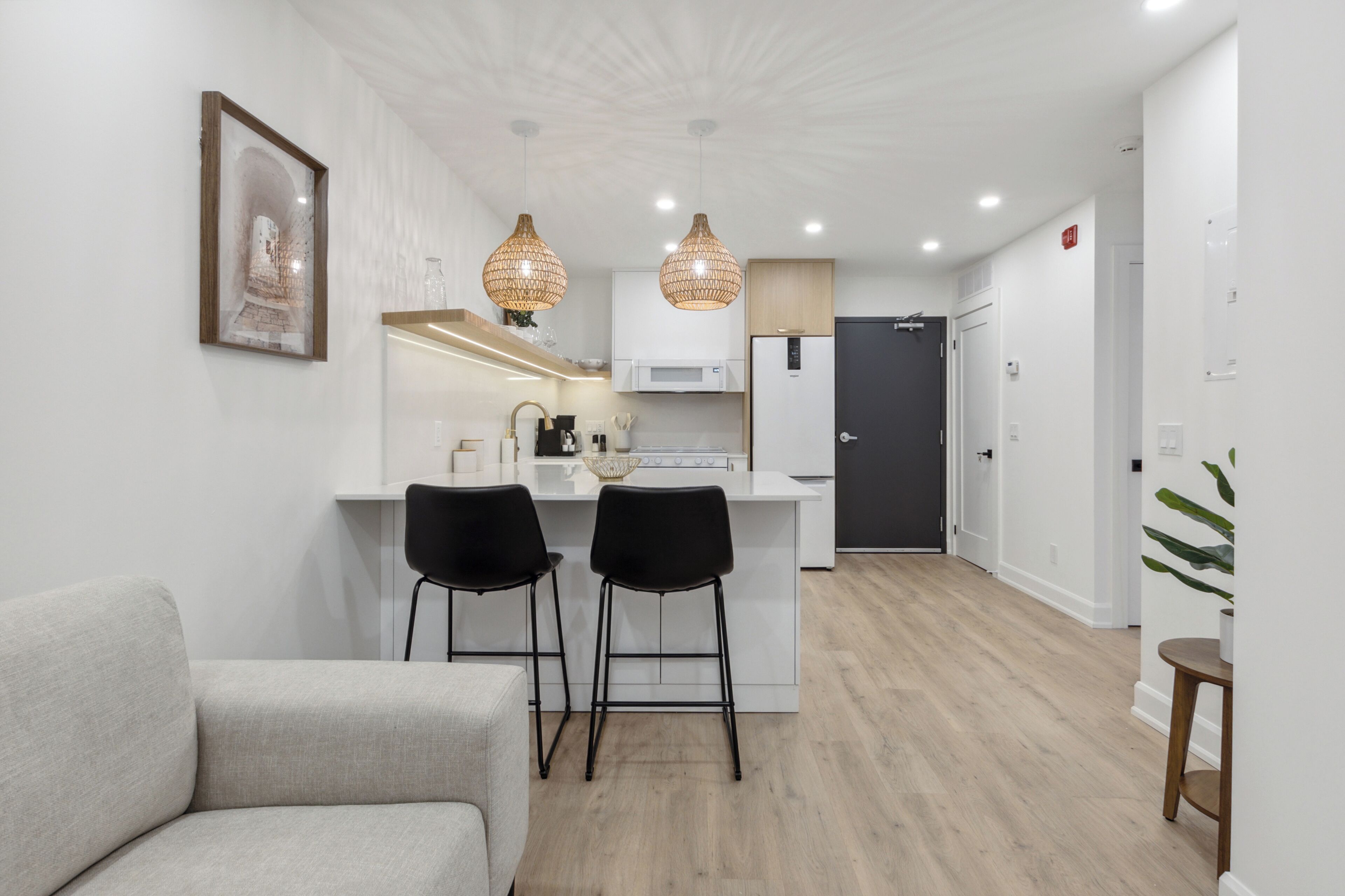 Cocina moderna con una isla central, dos taburetes negros y luces colgantes.