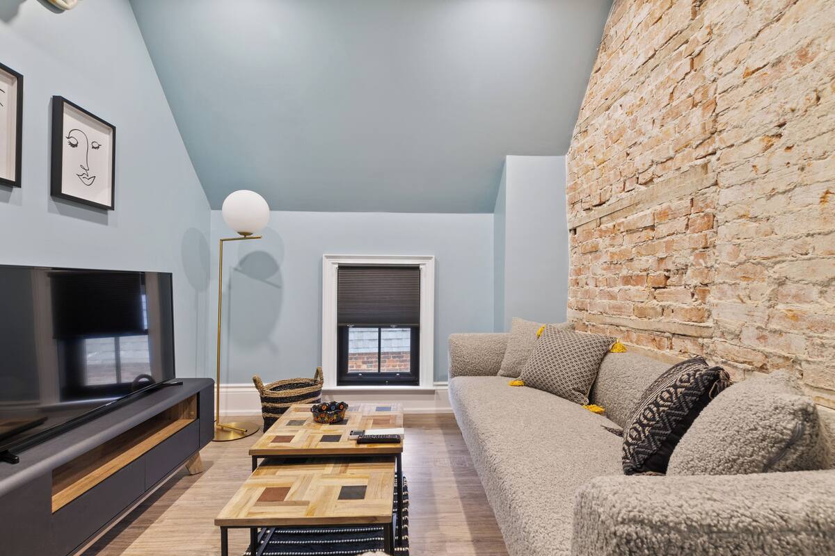Una sala de estar moderna con un televisor de pantalla plana, un sofá, una mesa de centro y una pared de ladrillo.