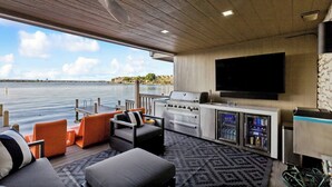 Eine moderne Terrasse im Freien mit Grill, Sitzgelegenheit und einem Flachbildfernseher.