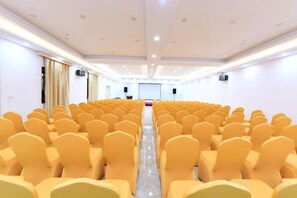 A conference room with rows of chairs, a stage, and a projector screen. - Shanshui Trends Hotel (Sha Village MTR station store Guangzhou) (Guangzhou)
